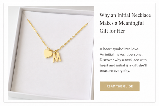 Gold necklace with heart and letter M initial displayed in a white jewelry box